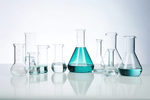 Laboratory equipment beakers and flasks with blue liquids with backlight in different group. AI Generated