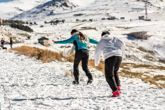 Icy adventures await! A Latino family revels in the snowy hills of Sierra Nevada, Granada, indulging in frosty fun