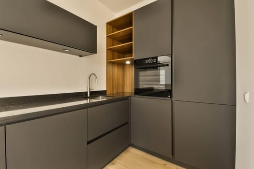 a modern kitchen with dark grey cabinets and black countertops on the wall, along with wooden flooring in an open space