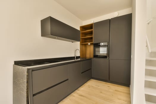a modern kitchen with wood flooring and black cabinetd cupboards in the center of the room is a white wall