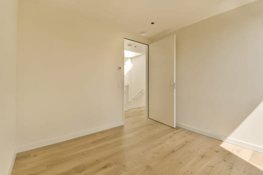 an empty room with white walls and wood flooring on the right, there is a door leading to another room