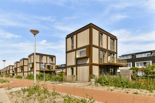 some houses that are in the middle of an urban area with plants and flowers growing on either side of the street