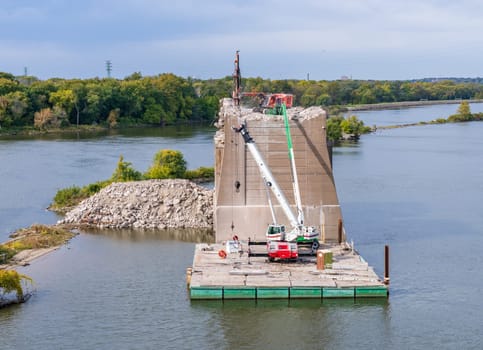 Heavy machinery removes the concrete pillars of historic I-74 bridge between Bettendorf Iowa and Moline Illinois