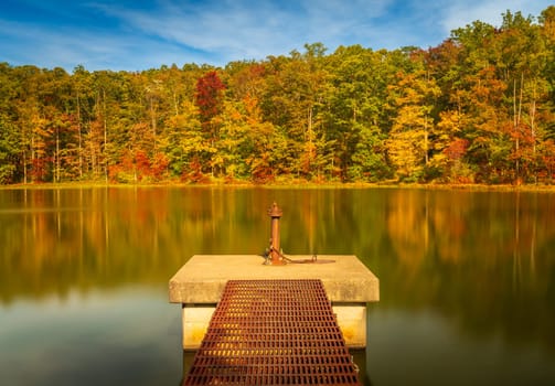 Changing leaves in autumn with metal walkway and platform in calm reservoir in Coopers Rock State Forest near Morgantown, WV