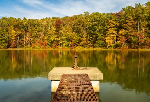 Changing leaves in autumn with metal walkway and platform in calm reservoir in Coopers Rock State Forest near Morgantown, WV