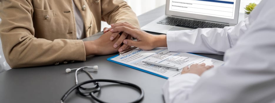 Doctor show medical diagnosis report and providing compassionate healthcare consultation while holding young patient hand for being supportive and professional in doctor clinic office. Neoteric