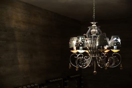 Close-up of antique chandelier with big yellow lightbulbs.