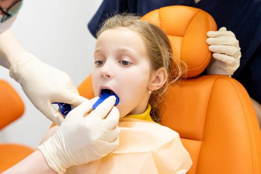The orthodontist prepares a special paste for making an impression of the patient's teeth.