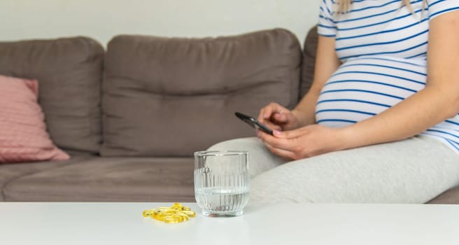 Pregnant woman drinks omega three. Selective focus. White.