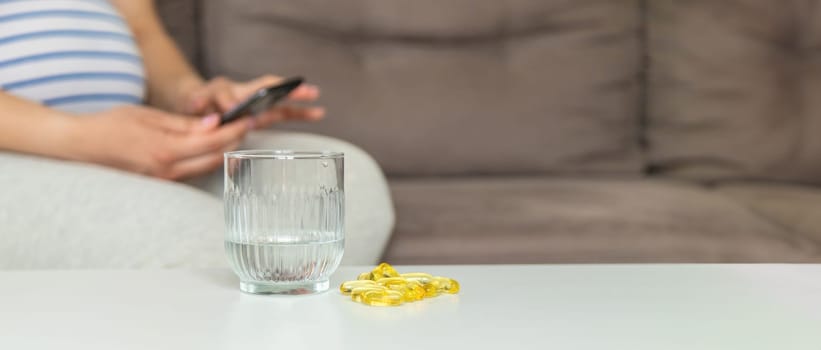 Pregnant woman drinks omega three. Selective focus. White.