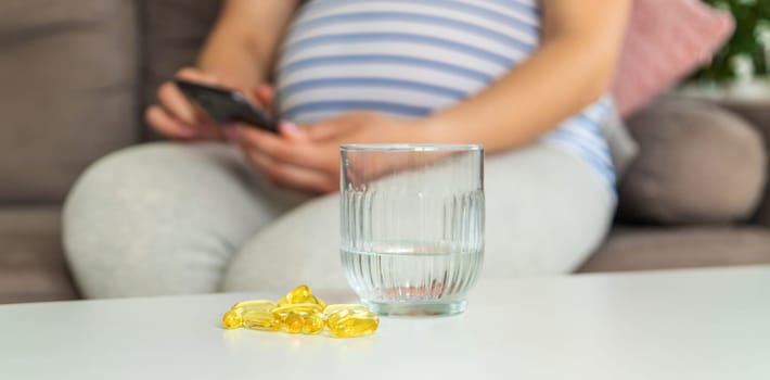 Pregnant woman drinks omega three. Selective focus. White.