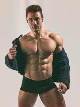 A Strong Display of Masculinity: Flexing Muscles and Striking a Pose in Studio. A man posing for a picture while flexing his muscles