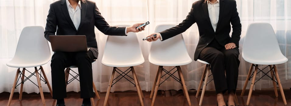 Job applicant sitting in on chair at waiting room with corridor, job seeker candidate talking, showing resume while waiting for job interview. Friendship in career opportunity concept. Trailblazing