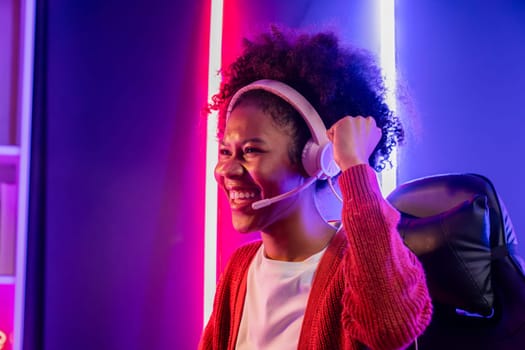 Gaming streamer, African girl playing online fighting with Esport skilled team wearing headphones in neon color lighting room. Talking other players planing strategies to win competitors. Tastemaker.