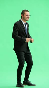 full-length portrait of a young man. standing isolated on green background.