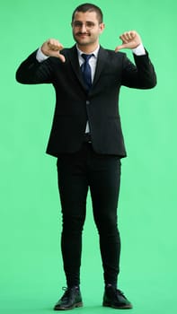 young man in full growth. isolated on green background showing thumbs down.