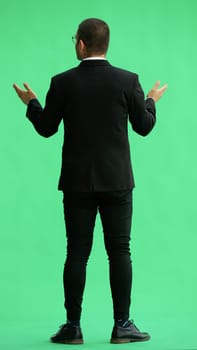 young man in full growth. isolated on green background demonstrates with hands.