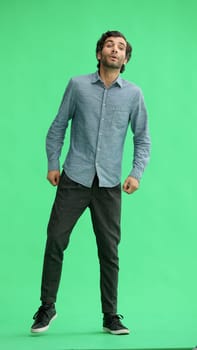 full-length portrait of a young man. standing isolated on green background.