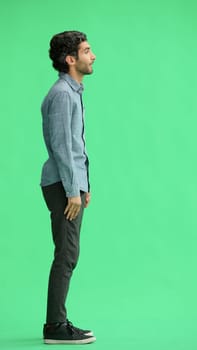 full-length portrait of a young man. standing isolated on green background.