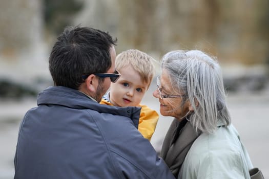 Gray-haired grandmother with a son and a grandson on a walk
