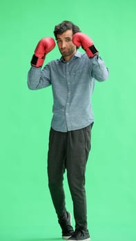 man isolated on a green background in business clothes with boxing gloves.