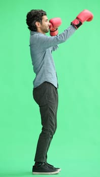 man isolated on a green background in business clothes with boxing gloves.