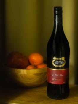 A high quality photo featuring wine and a bowl of fruit in the evening, with warm golden curtains soft over a wooden cutting board, this evocative image conjures a refined sense of depth, suggesting a still life from the baroque period in Europe, at once vintage and modern.