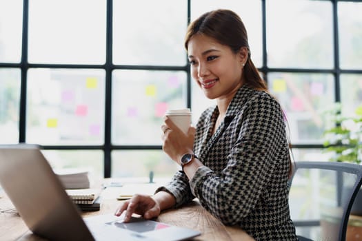 Portrait of a business woman talking on the computer and drinking coffee.