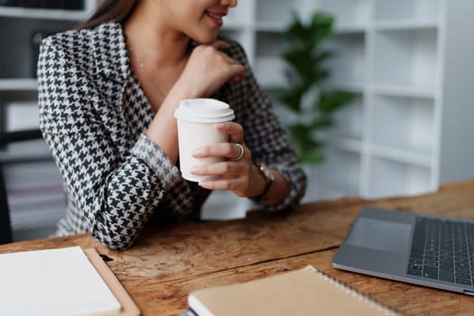 Portrait of a business woman talking on the computer and drinking coffee.