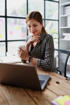 Portrait of a business woman talking on the computer and drinking coffee.