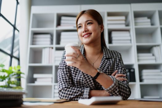 Portrait of a business woman talking on the computer and drinking coffee.