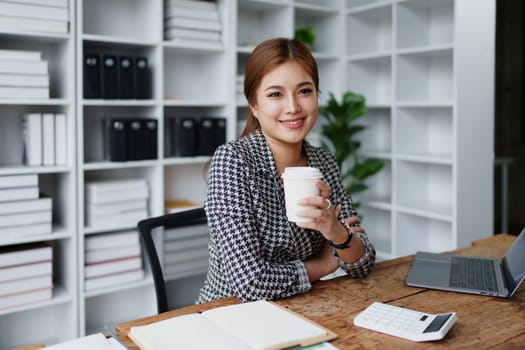 Portrait of a business woman talking on the computer and drinking coffee.