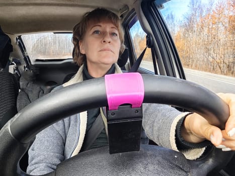 Portrait of female driver in solo journey. Adult mature woman holding steering wheel and looking through windscreen in travel by vehicle on vacation. Lady girl who is owner or rent car for travel