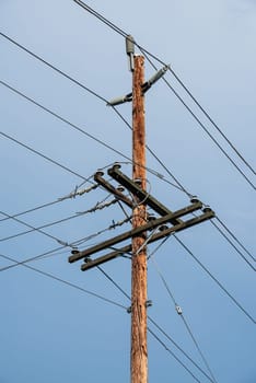 Electric pole and wires, wood electricty pole on blue sky background