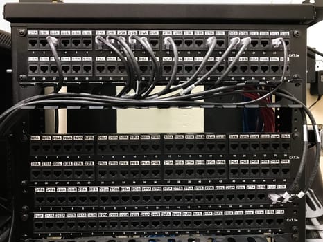 Enumerated ethernet patch panels with cables connected to the ports. Communication closet with patch panels mounted on the rack
