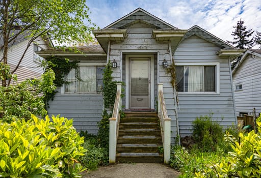 Neglected shabby old residential house on blue sky background