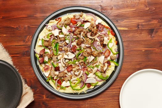 Raw St. Louis-Style Pizza homemade on a wooden background, with cheese, pepper, bacon onion