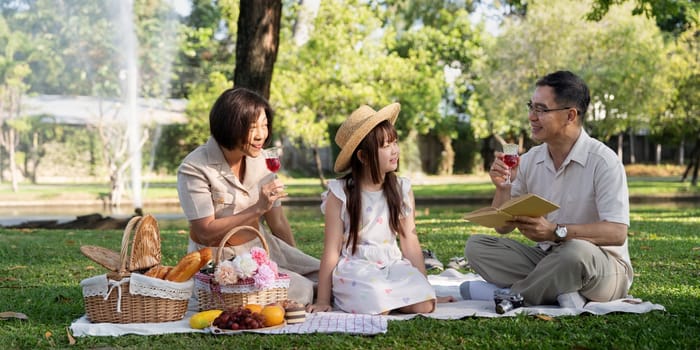 Happy senior grandparent together playing with little grandchild girl and party in park. Family leisure concept.