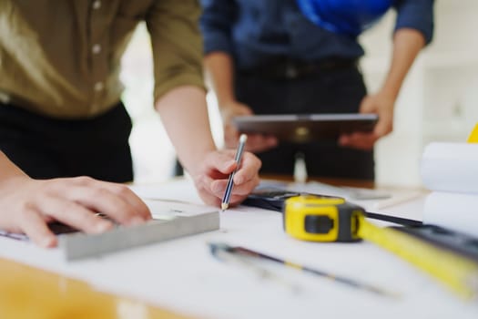 multi ethnic engineer brainstorming and measuring for cost estimating on paperworks and floor plan drawings about design architectural and engineering for houses and buildings.