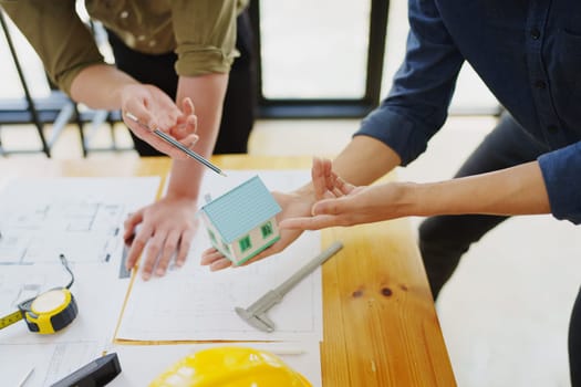 multi ethnic engineer brainstorming and measuring for cost estimating on blueprint and floor plan drawings about design architectural and engineering for houses and buildings.