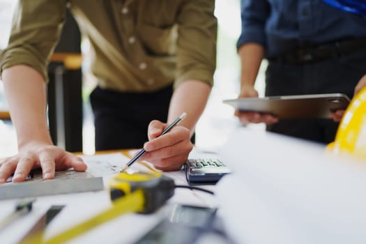 multi ethnic engineer brainstorming and measuring for cost estimating on paperworks and floor plan drawings about design architectural and engineering for houses and buildings.