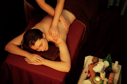 Caucasian woman customer enjoying relaxing anti-stress spa massage and pampering with beauty skin recreation leisure in warm candle lighting ambient salon spa at luxury resort or hotel. Quiescent