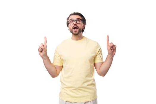 young brunette man in a t-shirt and glasses tells the news on a white background with copy space.