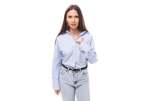 young stylish caucasian model woman with makeup and with dark straight hair dressed in a blue blouse on a white background with copy space.