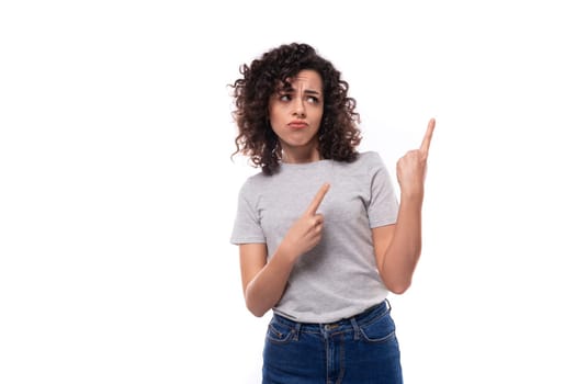 young active brunette curly woman dressed in a gray basic corporate color t-shirt actively gesturing with her hands on a white background with copy space.
