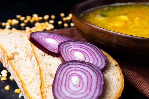 Appetizing hot pea soup and an onion served with slices of bread