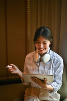 Pretty young creative woman with headphone working with digital tablet at office.