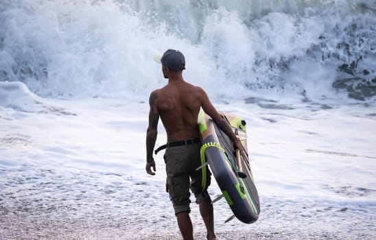 athletic wiry surfer guy swims with a paddle on a sup board in the sea Stand up paddleboarding