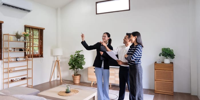 Young couple follow a real estate agent who is giving them a tour around a home, showing all the room and telling about all the advantage of living. Buying house or apartment concept.
