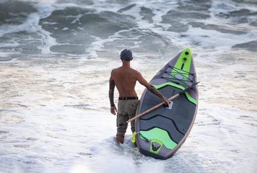 athletic wiry surfer guy swims with a paddle on a sup board in the sea Stand up paddleboarding